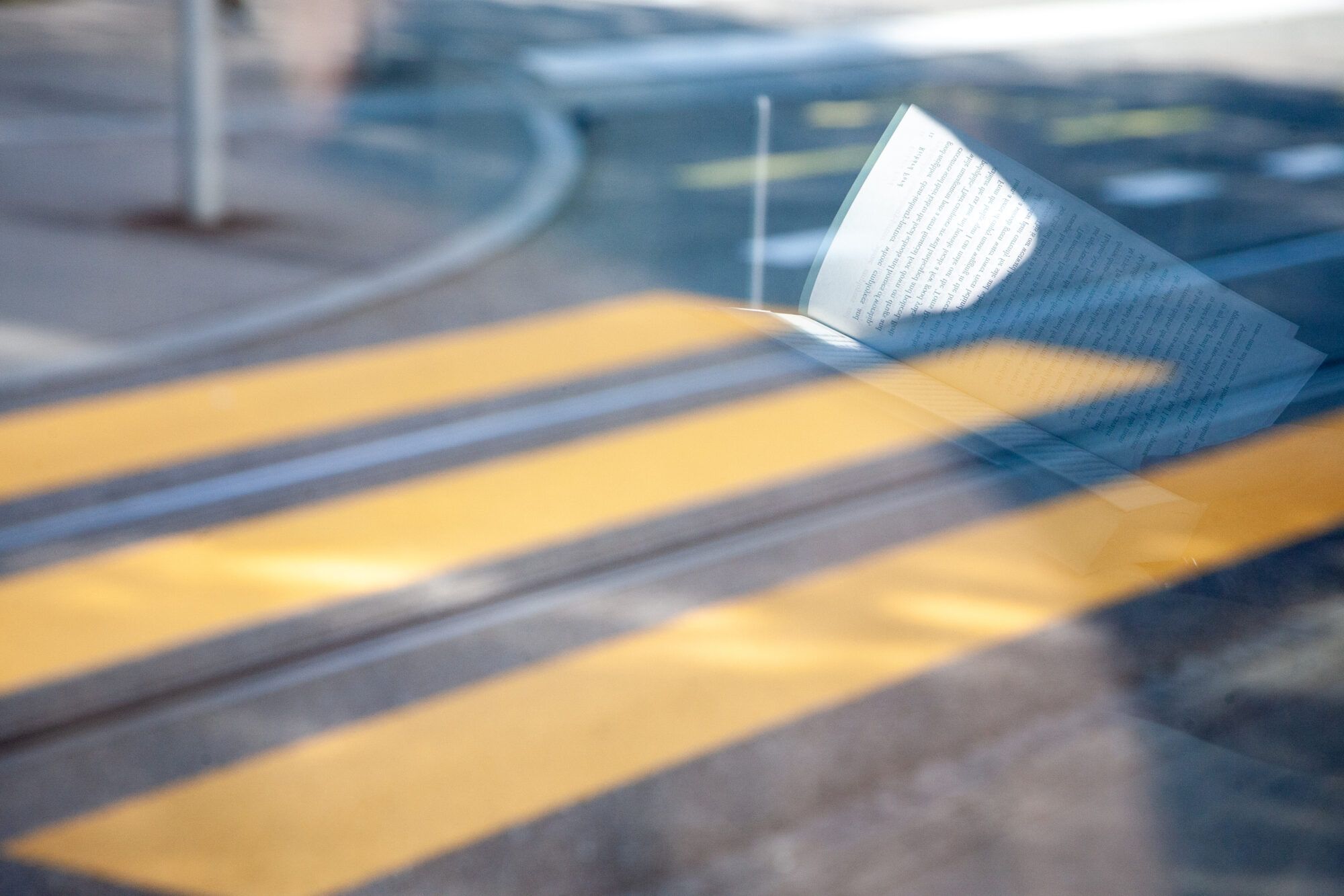 Spiegelung in Fenster mit gelben Zebrastreifen und Buch